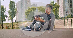 Closeup portrait of young strong African American male basketball player listening to music in vibes on his phone