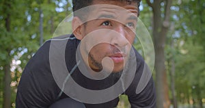 Closeup portrait of young strong African American male jogger preparing to run in the park being motivated outdoors