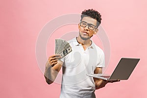 Closeup portrait, young successful african american business man making money from internet, holding cash in hand, laptop in