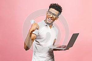 Closeup portrait, young successful african american business man making money from internet, holding cash in hand, laptop in