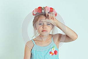 Kid giving loser sign on forehead looking at you disgust on face photo