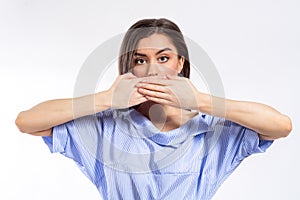 Closeup portrait of a young woman covering her mouth with her both hands. No freedom of speech, silence, concealment concept