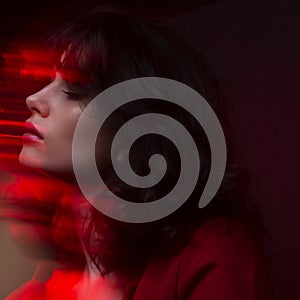 Closeup portrait of young woman with makeup and hairstyle, wear red suit, with closed eyes, red neon studio light.