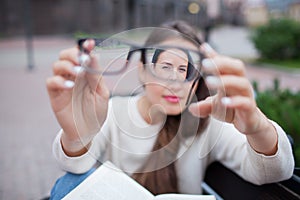 Closeup portrait of young women with glasses. She has eyesight problems and is squinting his eyes a little bit. Beautiful girl is