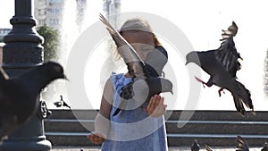 Closeup portreit of little cute girl feeding street pigeons in the park