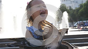 Closeup portreit of little cute girl feeding street pigeons in the park