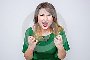 Closeup pose of an angry woman screaming in the green elegant dress