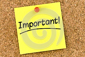 Closeup post it note on corkboard with important message on it
