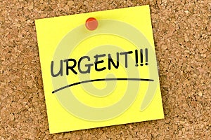 Closeup post it note on corkboard with urgent message on it