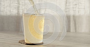 closeup pour ginger beer in a tumbler glass on oak table with copy space