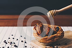 Closeup pouring honey to chocolate croissant.