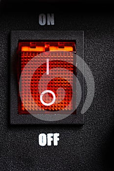 Closeup power switch on black background with red light.