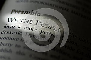 Closeup of the Preamble, We the People of the United States, printed and highlighted in textbook on white page.