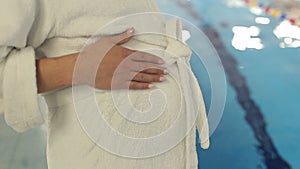 Closeup of pregnant woman`s belly in a white robe