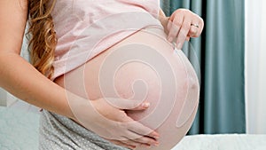 Closeup of pregnant woman walking with fingers acroos her bog belly. Concept of anticipation and waiting for baby