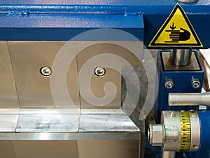 Closeup of pressing stamping hydraulic pressure automatic machine system with yellow precaution sign at heavy machinery plant