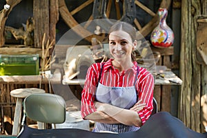 Closeup pretty craftsman female acting smile with arms crossed in his workplace with black leather pattern for working