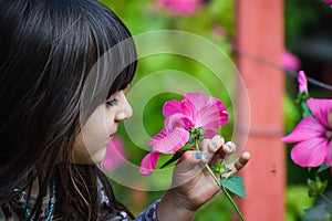 Closeup of pretty Little child Girl kid holding and smelling flowe