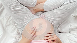 Closeup of pretty pregnant young woman touching and stroking her unborn baby in big belly. Beautiful pregnancy and
