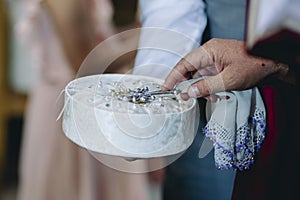 Closeup of priest in armenian church puts cross on the rings and blessing just married couples