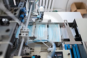 Closeup process of medical face masks being made in a factory. Automated machinery making respiratory medical masks in large