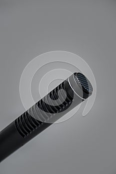Closeup of a professional black metal microphone for recording on gray background