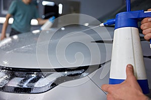 Closeup professional detailer hand applying auto body coating at car service