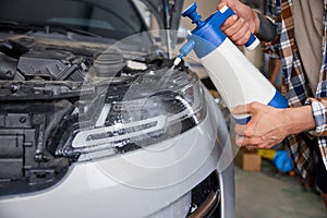 Closeup professional detailer hand applying auto body coating at car service