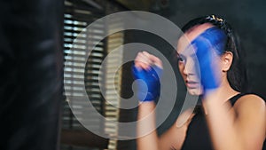 Closeup professional girl of mixed martial arts beating by arm in gloves at dark kickboxing studio