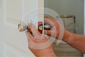 Closeup of a professional locksmith installing or repairing a new deadbolt lock photo