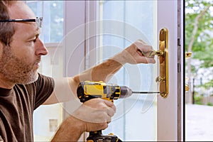 Closeup of a professional locksmith installing or repairing a new deadbolt lock photo