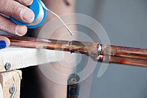 Closeup professional master plumber holding flux paste for soldering and brazing seams of copper pipe gas burner. Concept