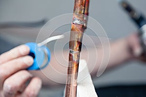 Closeup professional master plumber holding flux paste for soldering and brazing seams of copper pipe gas burner. Concept