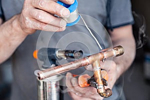 Closeup professional master plumber holding flux paste for soldering and brazing seams of copper pipe gas burner. Concept