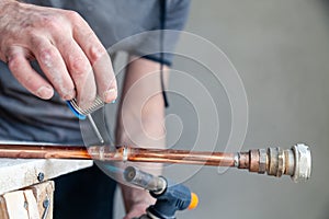 Closeup professional master plumber holding flux paste for soldering and brazing seams of copper pipe gas burner. Concept