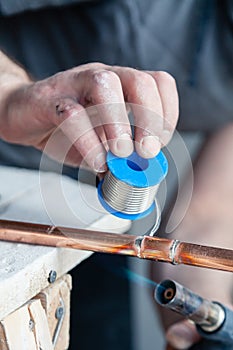 Closeup professional master plumber holding flux paste for soldering and brazing seams of copper pipe gas burner. Concept