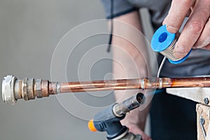 Closeup professional master plumber holding flux paste for soldering and brazing seams of copper pipe gas burner. Concept photo