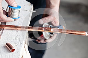 Closeup professional master plumber holding flux paste for soldering and brazing seams of copper pipe gas burner. Concept breaking