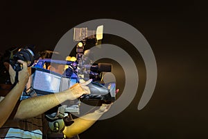 Closeup of professional television camera in event at night.