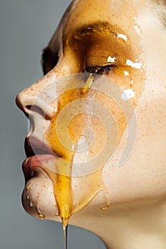 Closeup profile side view portrait of beautiful young brunette woman with freckles and honey on face with closed eyes and serious