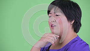 Closeup profile view of happy young overweight Asian woman thinking