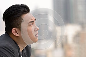 Closeup profile view of young overweight Asian businessman thinking