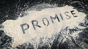 Closeup of PROMISE text written on white sand