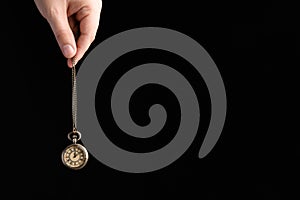 Closeup of psychotherapist with pendulum on black background, space for text. Hypnotherapy session