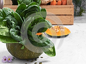 Closeup of a pumpkin with a bunch of fresh spinach. Freshly harvested vegetables in a wooden box turnips, beets, carrots, greens