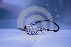 Closeup of quartz crystal necklace with leather string on purple background