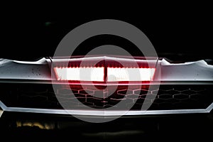 A closeup of a race cars left headlight with the colorful red and white detailing and the powerful shape. Speed drive