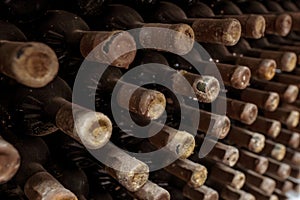 Closeup of a rack with old wine bottles covered in dust and cobweb in a winecellar in France photo