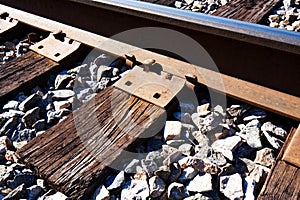 A closeup of a railroad rail, weathered cross ties and ballast.