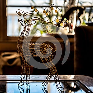 Closeup of a rain deer made of wire on the glass table window blurred background